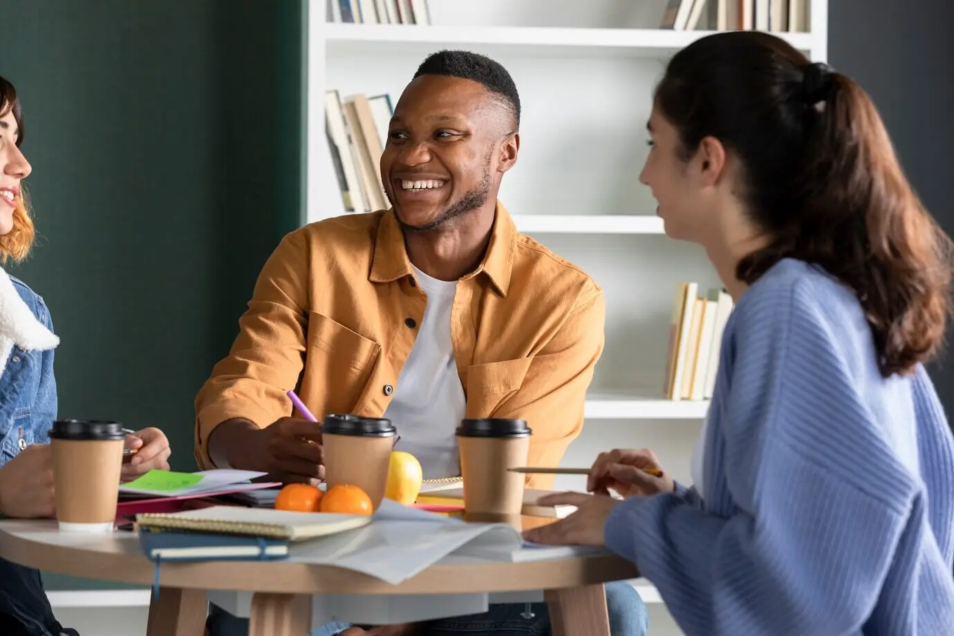 Junger Mann, der sich mit seinen Freunden unterhält und während einer Lernsitzung Notizen macht.