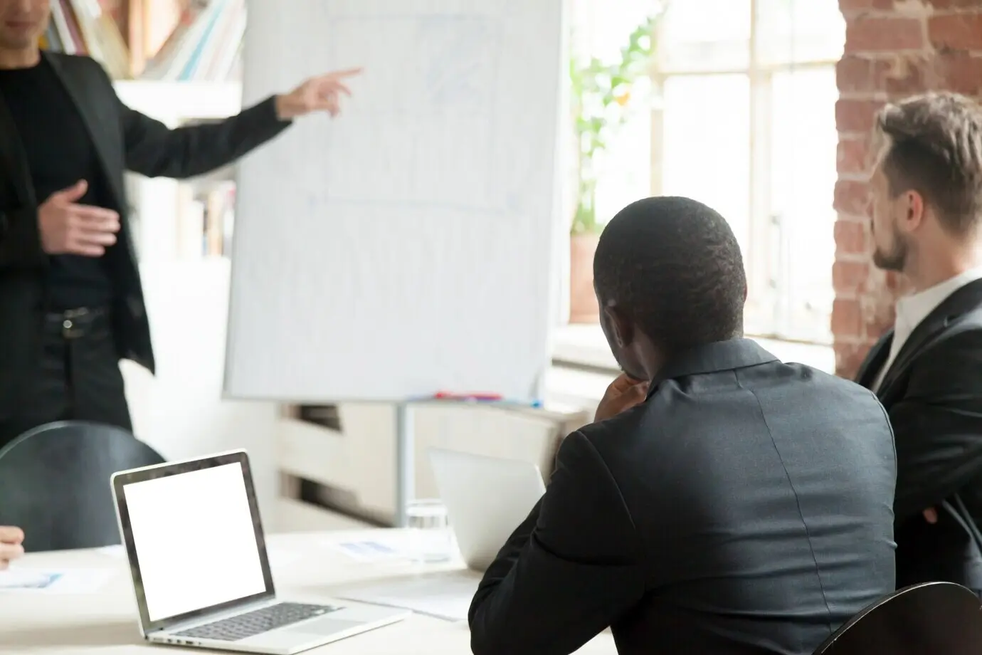 Ein Team von Geschäftsmännern hört während eines Briefings einem Geschäftsvortrag zu.